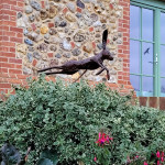 Leaping hare sculpture against cobbled wall stones