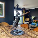Metal hare with gun sculpture sitting on wooden table in living room