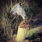 Metal horse head sculpture on tree stump part rusted