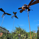 Three metal hornet sculptures against the blue sky in the garden