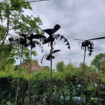 Metal hornet sculptures against grey clouds in the sky