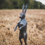 Hare sculpture standing on stubble field