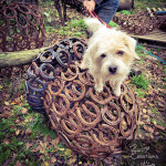 Dog sitting on top of Rusty Creations acorn sculpture