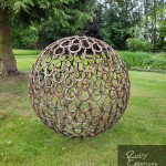 Large sculpture situated near tree made from recycled horseshoes