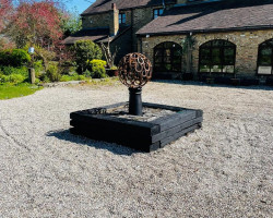 Metal sphere sculpture mounted on a plinth in situ on driveway