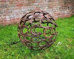 Horseshoe sphere sculpture in walled garden on grass