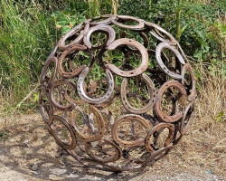 Sculpture made from metal horseshoes on dirt
