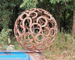 Rusty horseshoe sphere balanced on industrial beam