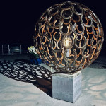 Sphere metal art on plinth lit up at night