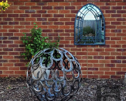 Horseshoe sphere sculpture in modern garden with mirror