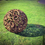Misfit sphere sculpture creating shadow on grass