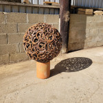 Metal sculpture mounted on chimney base outside Rusty Creations workshop